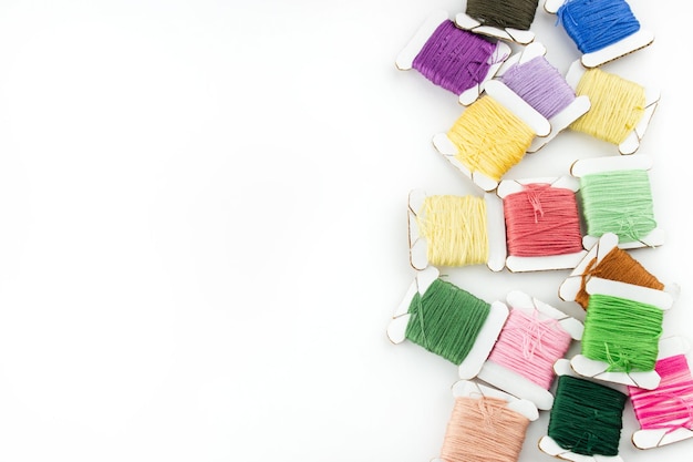 Igła i kolorowe nici na białym tle